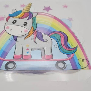 Può includere: Un arcobaleno colorato con un unicorno che cavalca uno skateboard. L'unicorno è grigio con una criniera e una coda arcobaleno. Lo skateboard è blu con ruote bianche.