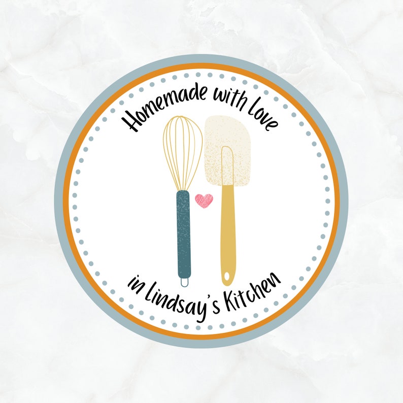 May include: A blue and orange circle with white polka dots and the text "Homemade with love in Lindsay's Kitchen". Inside the circle are illustrations of a whisk and a spatula with a pink heart between them.