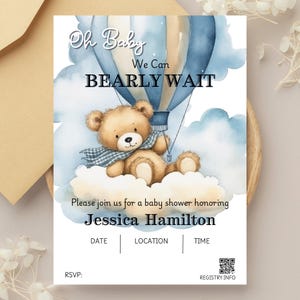 May include: A baby shower invitation featuring a watercolour illustration of a teddy bear in a blue and white hot air balloon. The text reads "Oh Baby We Can Bearly Wait".