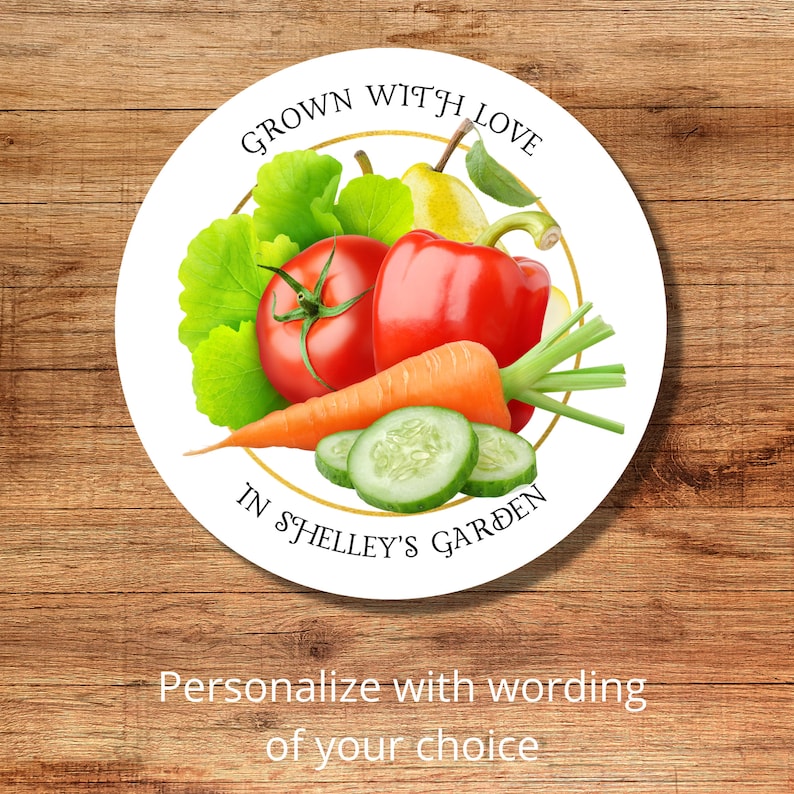 Op de afbeelding: Ronde witte sticker met een gouden cirkelrand. De sticker heeft een afbeelding van verse groenten en fruit, waaronder een tomaat, paprika, wortel, komkommer, peer en groene bladeren. De tekst op de sticker luidt "Grown with Love in Shelley's Garden".