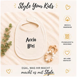Könnte beinhalten: Cremefarbene Baby-Lätzchen mit dem Text "Accio Brei" in Schwarz. Das Lätzchen ist oval geformt und hat eine Halsöffnung. Das Bild enthält auch einen Beißring aus Holz und den Text "Style Your Kids" und "Egal, was ihr macht - macht es mit Style."