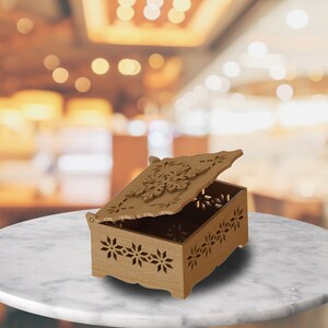 May include: A wooden box with a carved floral design and a hinged lid. The lid is open, revealing the interior of the box.