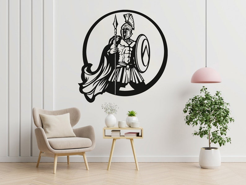 Puede incluir: Silueta en blanco y negro de un guerrero sosteniendo una lanza y un escudo, dentro de un c&iacute;rculo. El guerrero lleva un casco y una capa. La imagen est&aacute; sobre un fondo blanco.