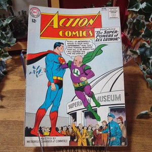May include: A vintage comic book cover featuring Superman and Lex Luthor. The cover is red, yellow, and blue with the title "Action Comics" and the text "Featuring The Super-Powers of Lex Luthor".