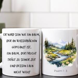 Könnte beinhalten: Weiße Keramiktasse mit einem schwarzen Zitat aus Psalm 1,3: "Er wird sein wie ein Baum, der am Wasser gepflanzt ist, der seine Frucht bringt zu seiner Zeit, und dessen Laub nicht welkt." Die andere Seite der Tasse zeigt eine Aquarellmalerei eines Baches, der durch ein grünes Tal mit Bergen im Hintergrund fließt.