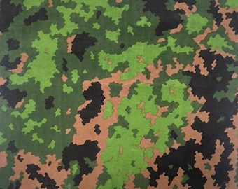 May include: A camouflage fabric pattern featuring green, brown and black colours. The pattern is made up of small, irregular shapes.