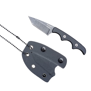 Könnte beinhalten: Ein kleines, graues Messer mit schwarzem Griff und passender Scheide. Auf der Klinge steht "Nordic Wolf Germany". Eine schwarze Kette ist an der Scheide befestigt.