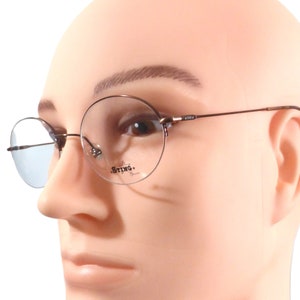 May include: Round, brown-framed glasses with a blue tint. The glasses have the word "Sting" printed on the right lens.
