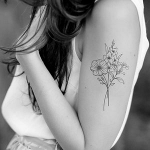 Vrouw met geboorte bloem boeket tattoo op boven arm. Minimalistische stijl lijn tekening zwart wit.