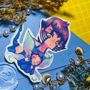 May include: A sticker featuring a colourful illustration of two characters. The larger character has purple hair and is wearing a blue and white outfit. The smaller character has brown hair and is wearing a blue and white outfit. Both characters have wings and are surrounded by a blue and white glow.