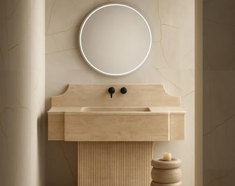 Op de afbeelding: Een modern badkamerinterieur met een beige stenen wastafel, zwarte kranen en een ronde verlichte spiegel. De muren en vloer zijn bedekt met bijpassende beige stenen tegels. Een houten bijzettafel completeert het minimalistische ontwerp.