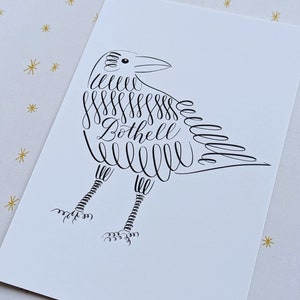 May include: A black and white illustration of a crow with the word "Bothell" written in cursive inside the crow's body.