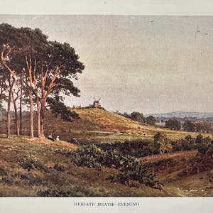 May include: A vintage landscape painting titled "Reigate Heath - Evening." The artwork depicts a rolling green hillside with a windmill, trees, and grazing animals. The sky is a soft, muted color, and the overall tone is warm and inviting.