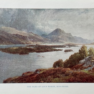 May include: An antique print of the Isles of Loch Maree, Ross-shire. The landscape features a lake surrounded by mountains and islands, with a cloudy sky overhead. The print has a vintage aesthetic.
