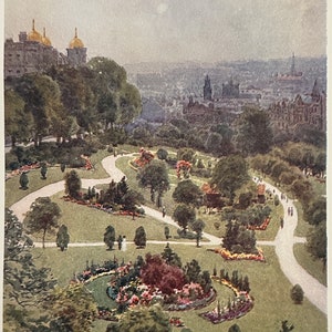 Puede incluir: Una vista aérea de un parque con caminos sinuosos y exuberante vegetación. El parque está lleno de flores coloridas y árboles. En la distancia, se puede ver el horizonte de una ciudad.