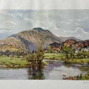 Op de afbeelding: Een vintage aquarel landschapsschilderij met een bergketen, een rivier en een grasveld met koeien. Het kunstwerk heeft een serene sfeer met zachte kleuren en een bewolkte lucht. De handtekening van de kunstenaar is zichtbaar.