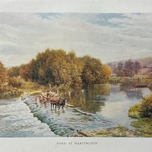 Puede incluir: Una pintura de acuarela vintage titulada "Ford at Harvington". La obra representa una escena de río con un equipo de bueyes tirando de un carro por el agua. Árboles frondosos bordean las orillas bajo un cielo nublado. La pintura tiene un aire clásico y pastoral.