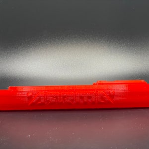 May include: A red 3D printed plastic part with the word "ASIRION" printed on it.