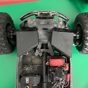 May include: A black and red remote control car with a black bumper and black wheels. The car has a black and red motor and a black and red battery pack. The car is on a green surface.