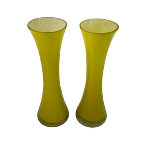 May include: Two yellow glass vases with a flared top and a slender, curved body. The vases have a smooth, glossy finish and a slightly lighter yellow interior. The vases are identical in shape and size.
