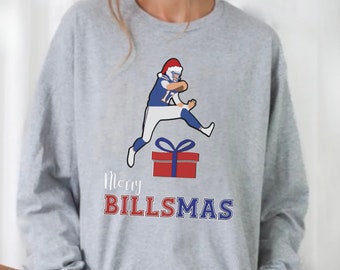 May include: A gray sweatshirt with a Christmas-themed design featuring a football player wearing a Santa hat jumping over a gift box. The text "Merry Billsmas" is printed below the image.