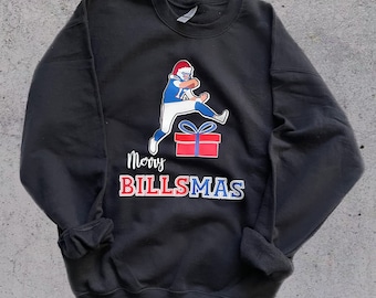 May include: Black sweatshirt with a graphic of a football player wearing a Santa hat and holding a football. The player is standing on top of a red gift box. The text "Merry Billsmas" is printed below the graphic.