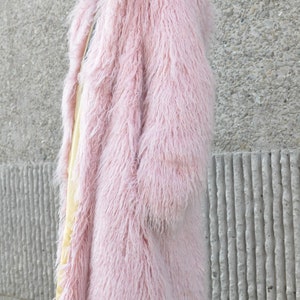 Puede incluir: Una larga y peluda chaqueta de piel sint&eacute;tica de color rosa.