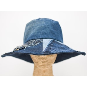 May include: A wide-brimmed sun hat made from blue denim patchwork. The hat has a wide brim and is made from different pieces of denim sewn together.