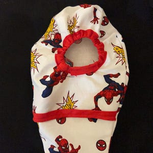 May include: White fabric diaper cover with a red elastic waistband and a red trim. The fabric features a repeated pattern of Spiderman in various poses with the word "THWIP" in yellow letters.