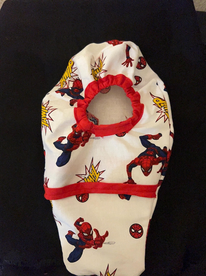 May include: White fabric diaper cover with a red elastic waistband and a red trim. The fabric features a repeated pattern of Spiderman in various poses with the word "THWIP" in yellow letters.