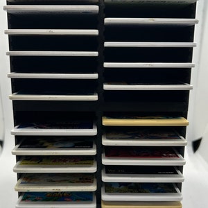 May include: Black plastic storage case with the text "HuCARD" and "TURBOGRAFX 16" in orange. The case has 16 slots for storing video game cartridges. The slots are filled with various game cartridges.