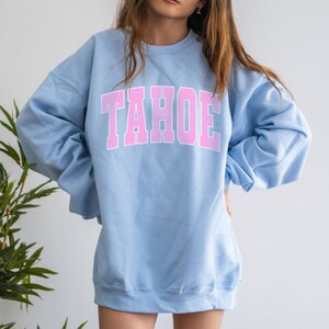 May include: A light blue sweatshirt with the word "TAHOE" printed in pink on the front.
