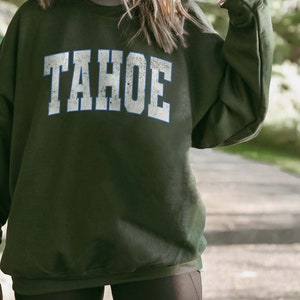 May include: A dark green sweatshirt with the word "TAHOE" printed in white with a blue outline.