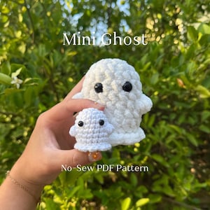 May include: Two white crochet ghosts with black eyes. The larger ghost is approximately 10 cm tall, and the smaller one is about 5 cm tall. The image includes the text "Mini Ghost" and "No-Sew PDF Pattern".