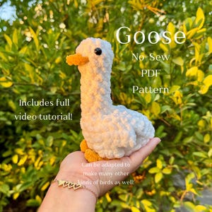 May include: A white goose plush toy with a yellow beak and feet. The image includes text that reads "Goose No-Sew PDF Pattern" and "Includes full video tutorial!" The plushie is held in a hand against a backdrop of green leaves.