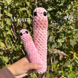 May include: Two plush, pink worms with black button eyes. One worm is larger than the other. The text "Worm" is above the worms, and "No-Sew PDF Pattern" is to the right.