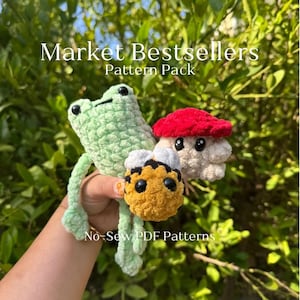 May include: Crocheted frog, mushroom, and bee amigurumi toys. The frog is light green, the mushroom has a red cap, and the bee is yellow and black. The image includes the text "Market Bestsellers Pattern Pack" and "No-Sew PDF Patterns".