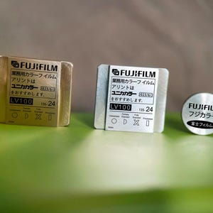 May include: Three gold and silver metal film canisters with the text "FUJIFILM" and "ユニカカラー" printed on them. The canisters are labeled "LV100" and "135-24".