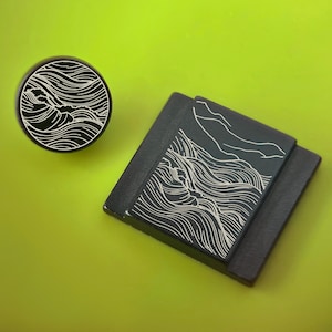May include: A black round plug and a square, layered object with a wave design in white. The objects are on a bright green background. The wave design is a series of curved lines.