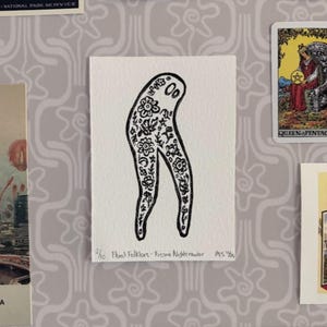 Può includere: Illustrazione in bianco e nero di una creatura stilizzata con motivi floreali. L'opera, intitolata "Floral Folklore - Fresno Nightcrawler", è su una carta rettangolare bianca. La carta è esposta con altri oggetti effimeri vintage.