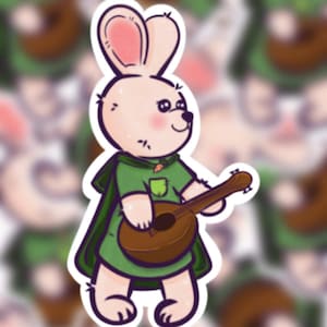 May include: A sticker of a cartoon bunny playing a brown ukulele. The bunny is dressed in a green cape and shirt with a small pocket and a carrot detail. The bunny has pink inner ears and rosy cheeks.