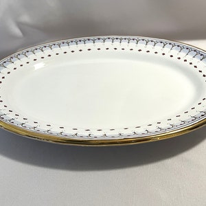 May include: White oval serving platter with a gold rim and a decorative border of red and blue accents.