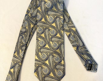 May include: A yellow necktie with a repeating paisley pattern in navy blue and light blue. The tie is made of a shiny material and is displayed flat. The paisley design is a classic and elegant choice for formal or business attire.