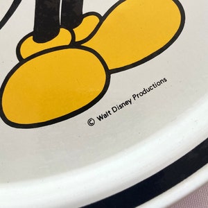 May include: White ceramic plate with a black border. The plate features a cartoon image of Mickey Mouse's feet with yellow shoes and black outlines. The text "&copy; Walt Disney Productions" is printed on the plate.