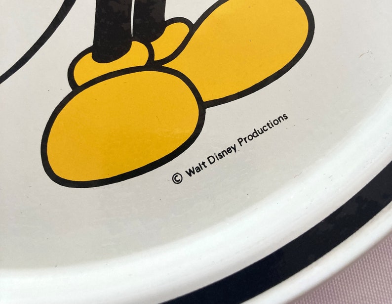 May include: White ceramic plate with a black border. The plate features a cartoon image of Mickey Mouse's feet with yellow shoes and black outlines. The text "&copy; Walt Disney Productions" is printed on the plate.