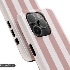 May include: A white and pink striped phone case with a camera cutout. The case is made of a tough material and is designed to protect your phone from scratches and drops. Tough Phone Case.