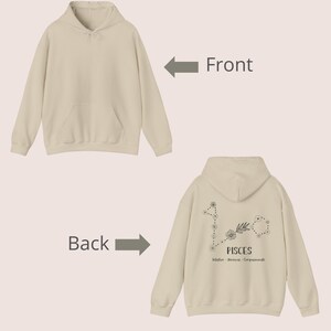 Puede incluir: Una sudadera con capucha de color crema con un bolsillo en la parte delantera y un dise&ntilde;o de constelaci&oacute;n zodiacal de Piscis en la parte posterior. El dise&ntilde;o incluye las palabras "Piscis", "Intuitivo", "So&ntilde;ador" y "Compasivo".