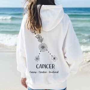 Puede incluir: Sudadera blanca con un signo zodiacal de C&aacute;ncer floral negro y el texto "Caring - Creative - Emotional".