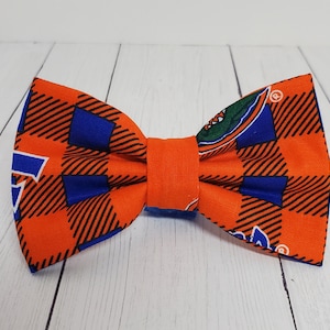 May include: Orange and blue bow tie with a plaid pattern and a small logo in the center.