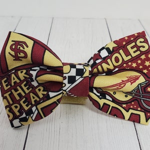May include: A red, yellow, and white bow tie with a Seminole State University logo and the words "Fear the Spear" and "Noles".